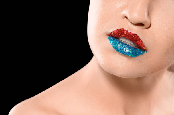 Beautiful young model with creative lips makeup on black background - Photo, image
