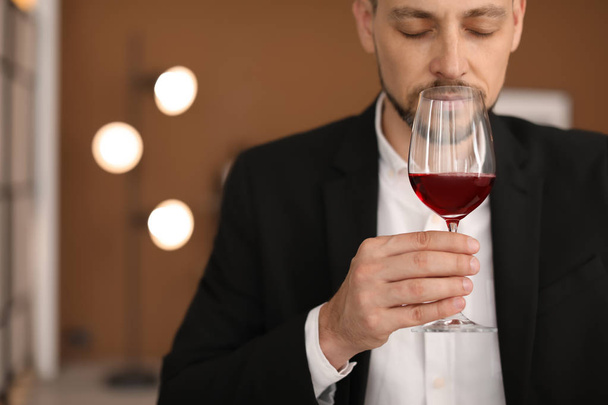 Young man with glass of wine indoors - Foto, afbeelding