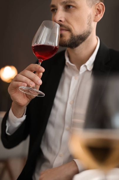 Young man with glass of wine indoors - Fotoğraf, Görsel