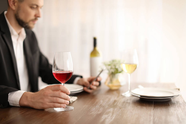 Man with glass of wine at table in restaurant - Valokuva, kuva