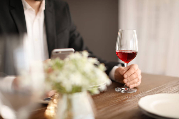 Homme avec un verre de vin à table au restaurant
 - Photo, image