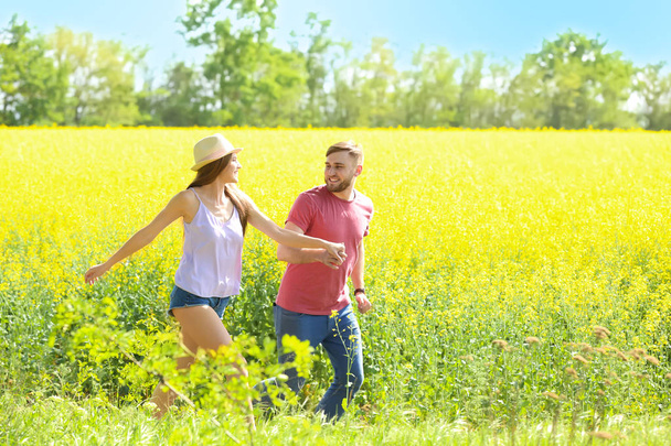 Happy young couple in green field on sunny spring day - Фото, зображення