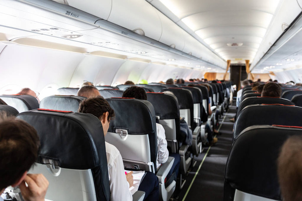 Interior de un gran avión comercial con pasajeros en sus asientos durante el vuelo
. - Foto, Imagen