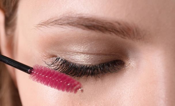 Attractive young woman applying mascara on her eyelashes, closeup - Fotoğraf, Görsel