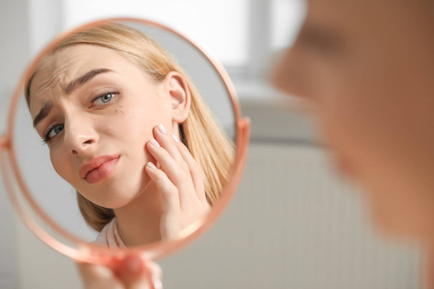 Young woman with eyelash loss problem looking in mirror indoors - Φωτογραφία, εικόνα