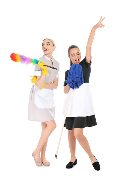 Camareras jóvenes con cepillo de polvo y fregona sobre fondo blanco
 - Foto, Imagen
