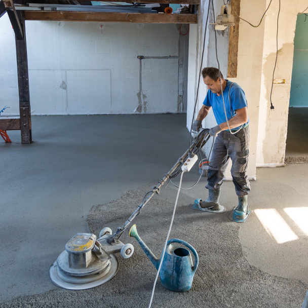 Laborer polishing sand and cement screed floor. - Photo, Image