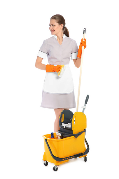 Young chambermaid with cleaning supplies on white background - Foto, Imagen