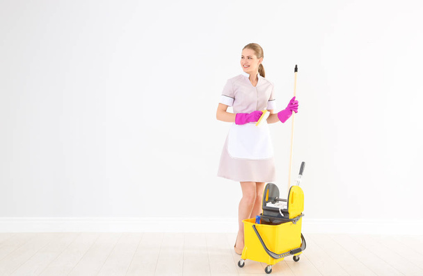 Young chambermaid with cleaning supplies indoors - Photo, image
