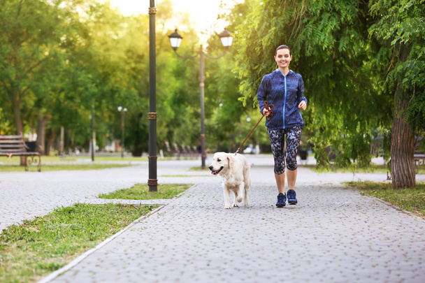 Young woman with her dog together in park. Pet care - Fotoğraf, Görsel