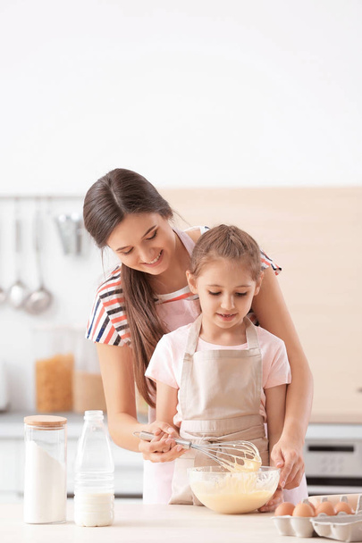 Mother and her daughter making dough at table in kitchen - Photo, Image