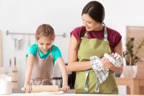 Mother and her daughter preparing dough at table in kitchen - Foto, Imagen
