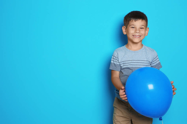 Cute boy with balloon on color background. Birthday celebration - Photo, image