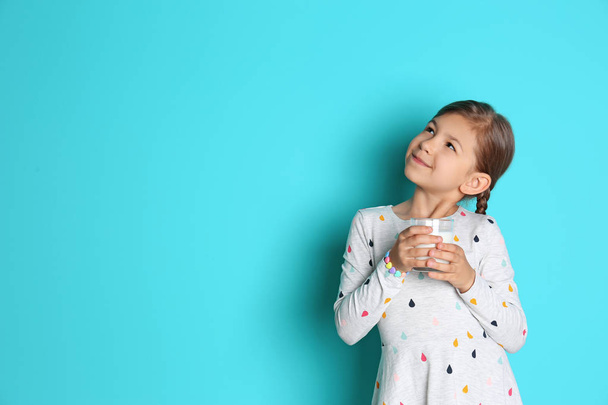 Cute little girl with glass of milk on color background - Photo, image