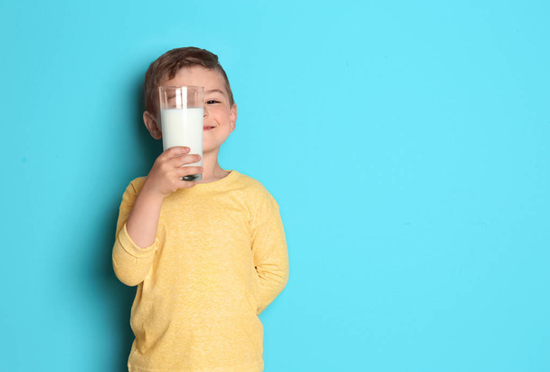 Χαριτωμένο μικρό αγόρι με το ποτήρι γάλα σε χρώμα φόντου - Φωτογραφία, εικόνα