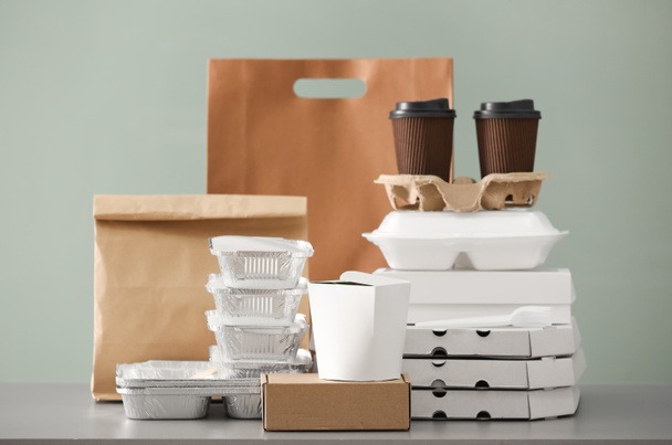 Farklı paketler ve karton bardak renk arka plan karşı masada. Gıda dağıtım hizmeti - Fotoğraf, Görsel