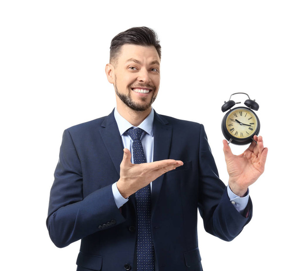 ホワイトを背景に目覚まし時計を持つビジネスマン。時間管理の考え方 - 写真・画像