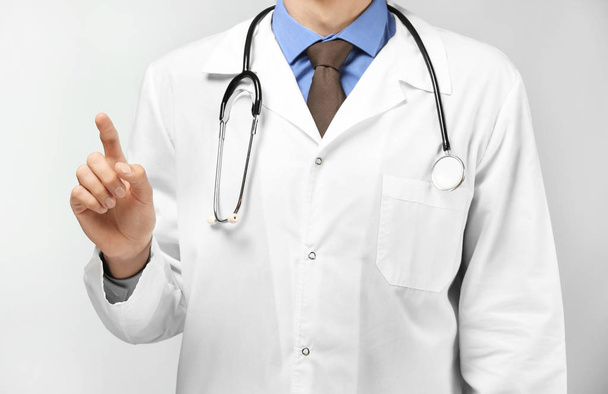 Médico masculino mostrando algo no fundo branco
 - Foto, Imagem