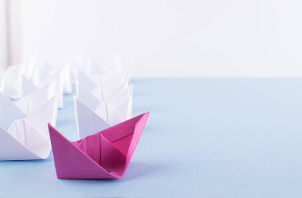 Egy egyedülálló rózsaszínű papír csónak között sok is. Különböző papír hajók egyéniség és a vezetői koncepció - Fotó, kép