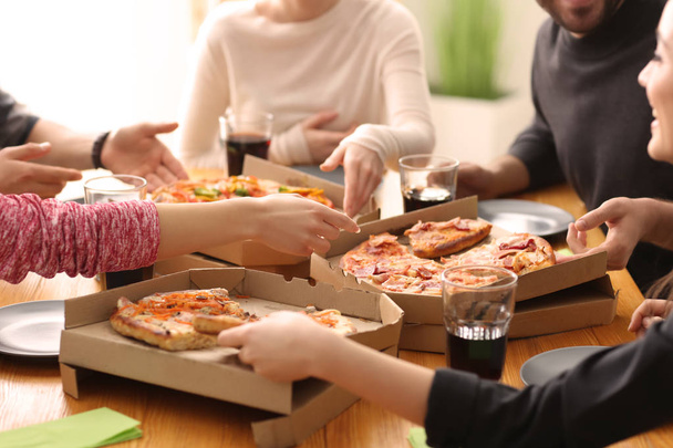 Les jeunes mangent de la pizza à table à l'intérieur
 - Photo, image