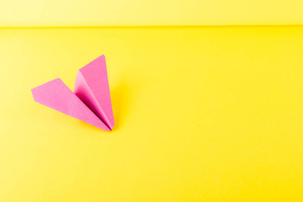 rosa Papierflugzeug oder Papierflugzeug Origami auf gelbem Hintergrund von oben mit Platz für Text - Foto, Bild