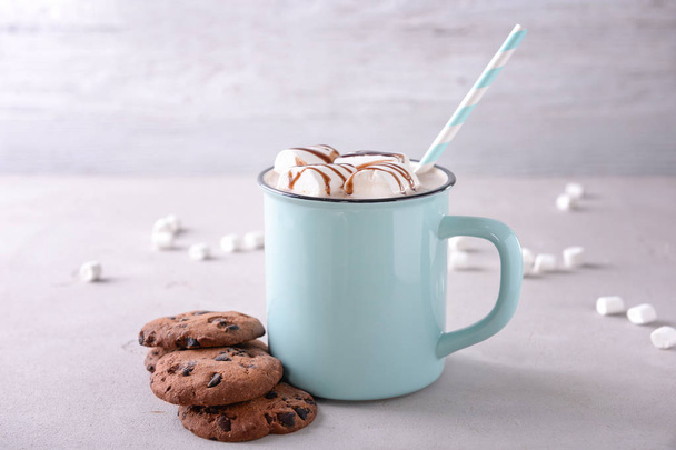 Metal cup of delicious cocoa drink with marshmallows and cookies on table - Фото, зображення