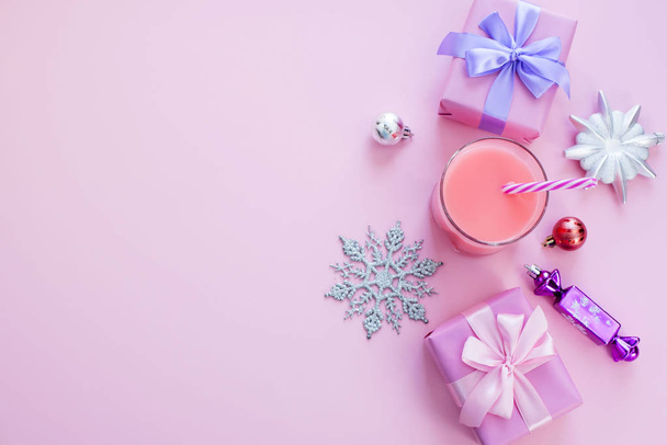 Kerst samenstelling Flat leg dozen met geschenken satijn lint boog Christmas speelgoed sneeuwvlokken. Decoratief frame bovenaanzicht roze achtergrond - Foto, afbeelding