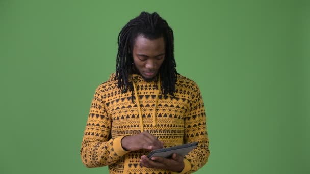 Young handsome African man with dreadlocks against green background - Video