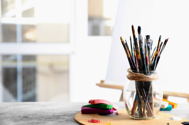 Veel verf penselen met houten palet op tafel binnenshuis - Foto, afbeelding