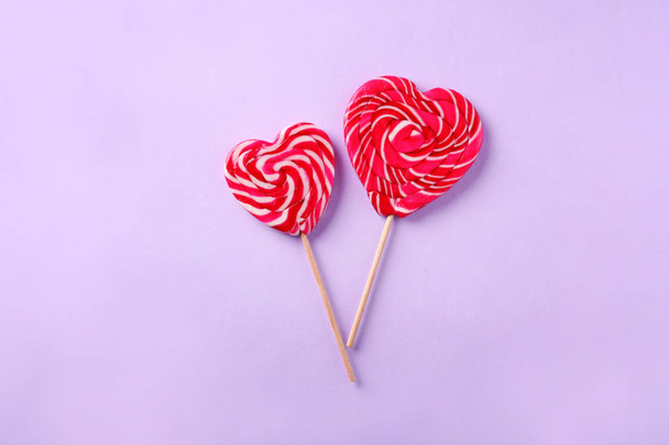 Heart shaped lollipops on color background - Фото, изображение