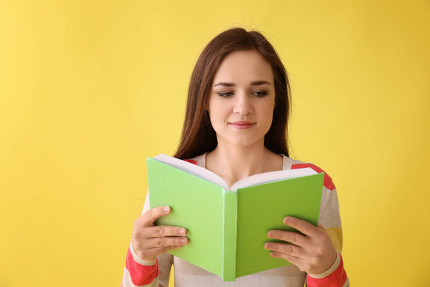 Young woman with book on color background - Фото, изображение