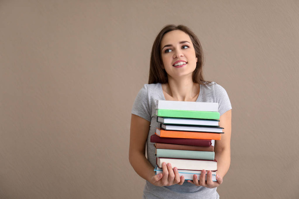 Young woman with stack of books on color background - Foto, Imagem