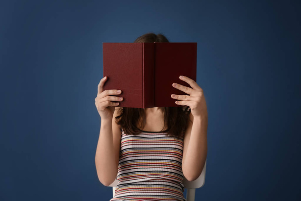 Young woman reading book on color background - Foto, imagen