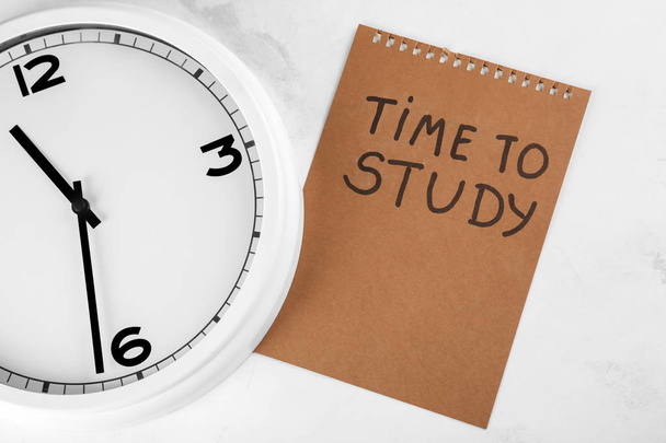 Klok en vel papier met inscriptie tijd aan studie op lichte achtergrond. Time management concept - Foto, afbeelding