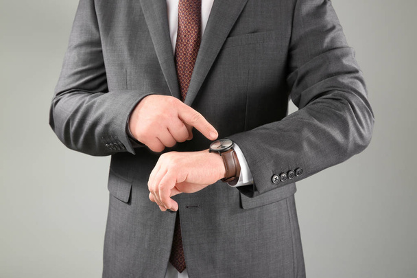 Man with wrist watch against grey background. Time management concept - Photo, Image