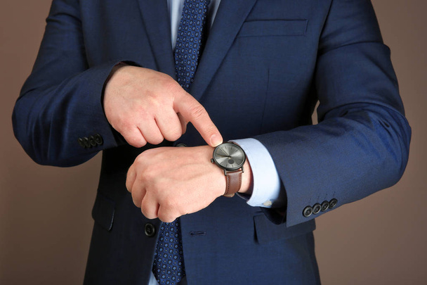 Człowiek z zegarek na rękę przeciwko kolor tła. Koncepcja zarządzania czasu - Zdjęcie, obraz