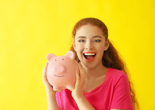 Mladá žena držící prasátko na barvu pozadí. Koncept úspory peněz - Fotografie, Obrázek