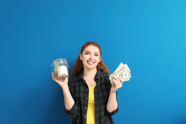 Young woman holding glass jar with dollar banknotes on color background. Money savings concept - Fotografie, Obrázek