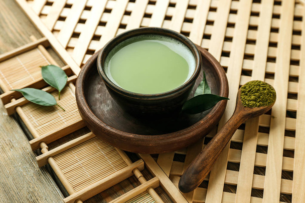 Fresh matcha tea in bowl and spoon with powder on wooden tray - Фото, зображення