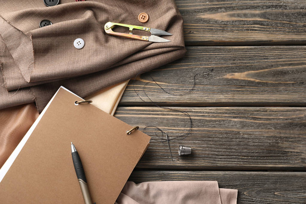 Notebook en naaien accessoires op houten achtergrond - Foto, afbeelding