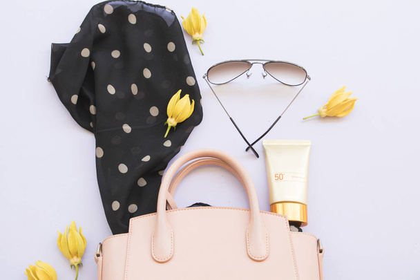 солнцезащитный крем spf50, розовая сумка, солнцезащитные очки и черные шарфы аксессуары образа жизни женщины расслабиться на заднем плане белого
 - Фото, изображение