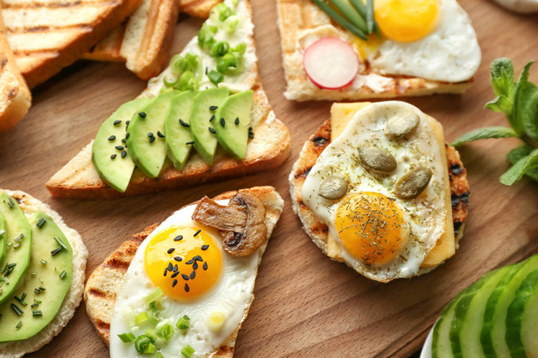 Different delicious toasts on wooden board - Photo, Image