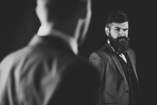 Meeting of reputable businessmen, black background. Man with beard on suspicious face, and shoulders of partner, defocused. Business meeting concept. Businessmen, business partners in formal wear - Фото, изображение