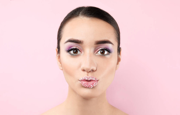 Όμορφη νεαρή γυναίκα με δημιουργικό μακιγιάζ στο φόντο χρώμα - Φωτογραφία, εικόνα