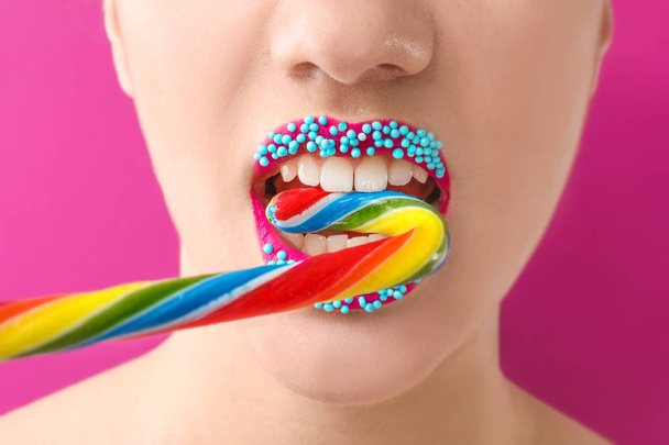 Красивая молодая женщина с творческим макияжем и конфеты трость на цветном фоне, крупным планом
 - Фото, изображение