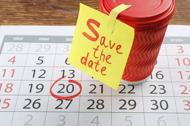 Copa, hoja de papel con texto "Guardar la fecha" y calendario en la mesa de madera
 - Foto, Imagen