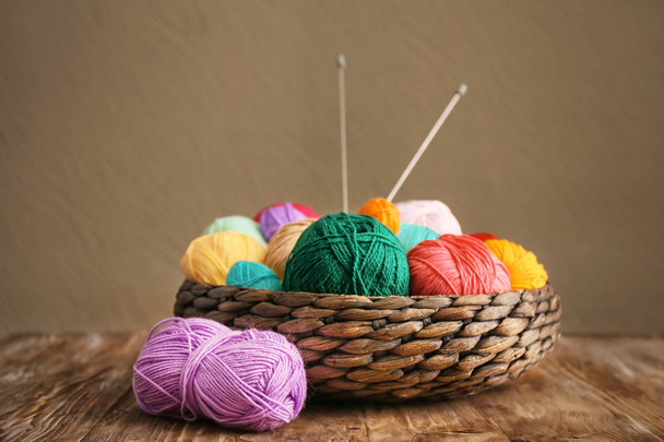 Panier en osier avec fil à tricoter sur table en bois
 - Photo, image