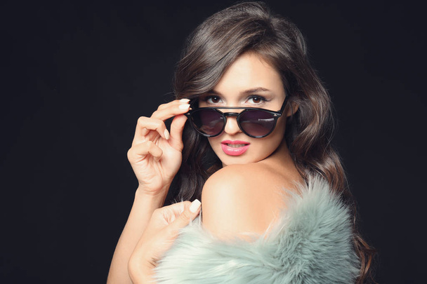Beautiful stylish woman with sunglasses on dark background - Foto, afbeelding
