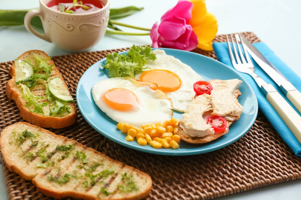 Placa con pan tostado, huevos fritos y pollo sobre estera de mimbre
 - Foto, Imagen