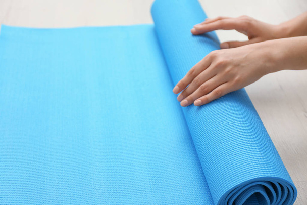 Jonge vrouw met yoga mat binnenshuis, close-up - Foto, afbeelding